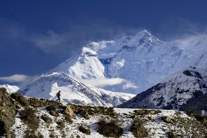 Rinzin Phunjok Lama camina por la región de Humla, con la cumbre de Annapurna de fondo.