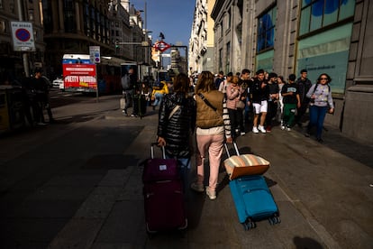 Dos mujeres con maletas pasean por la Gran Vía de Madrid.