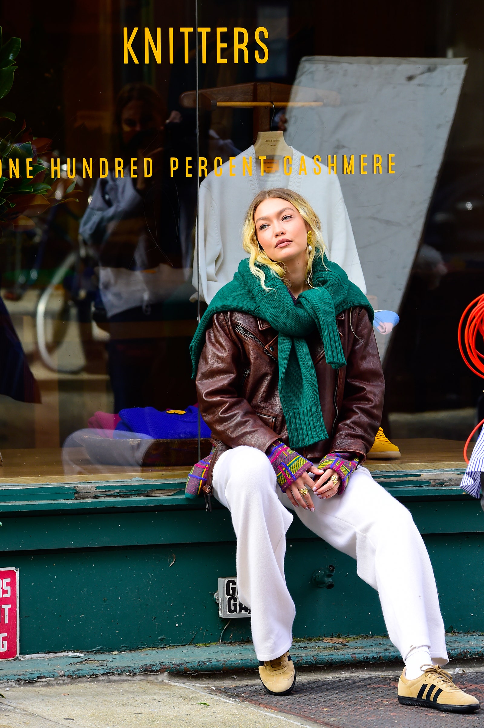 Image may contain Gigi Hadid Clothing Coat Jacket Pants Footwear Shoe Adult Person Sitting Accessories and Bag