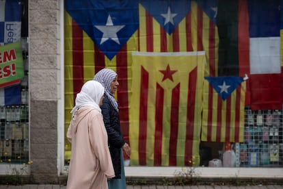 Dos mujeres caminan por delante del escaparate de un bazar donde cuelgan banderas 'estelades' (independentistas) esta semana.