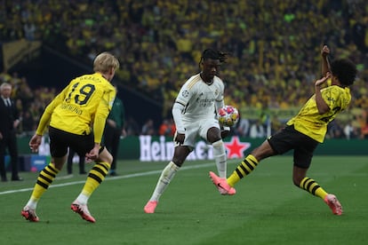 El centrocampista francés del Real Madrid Eduardo Camavinga disputa un balón ante el defensa neerlandés Ian Maatsen y el alemán Brandt del Dortmund.
