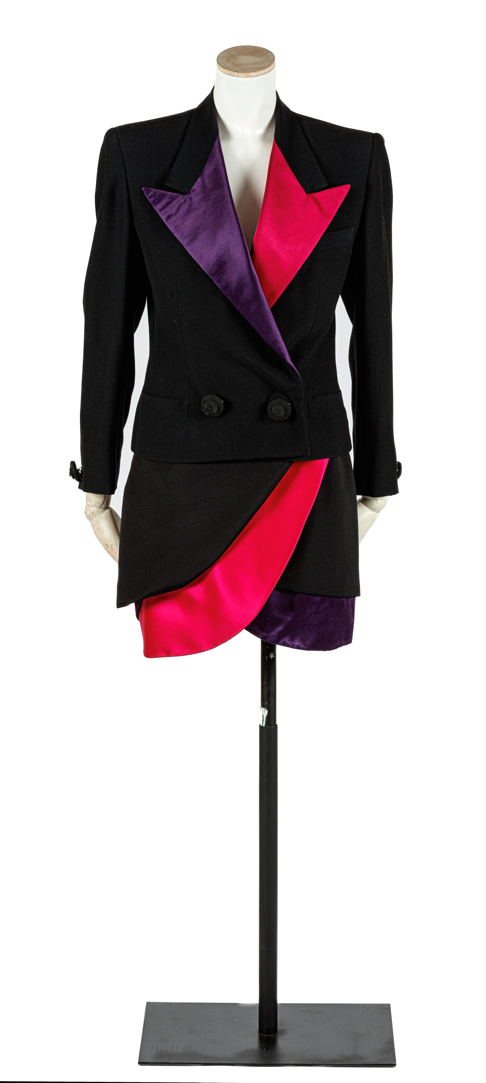 Traje negro de chaqueta entallada y solapas de color morado y fucsia y falda corta a capas negra morada y fucsia.
