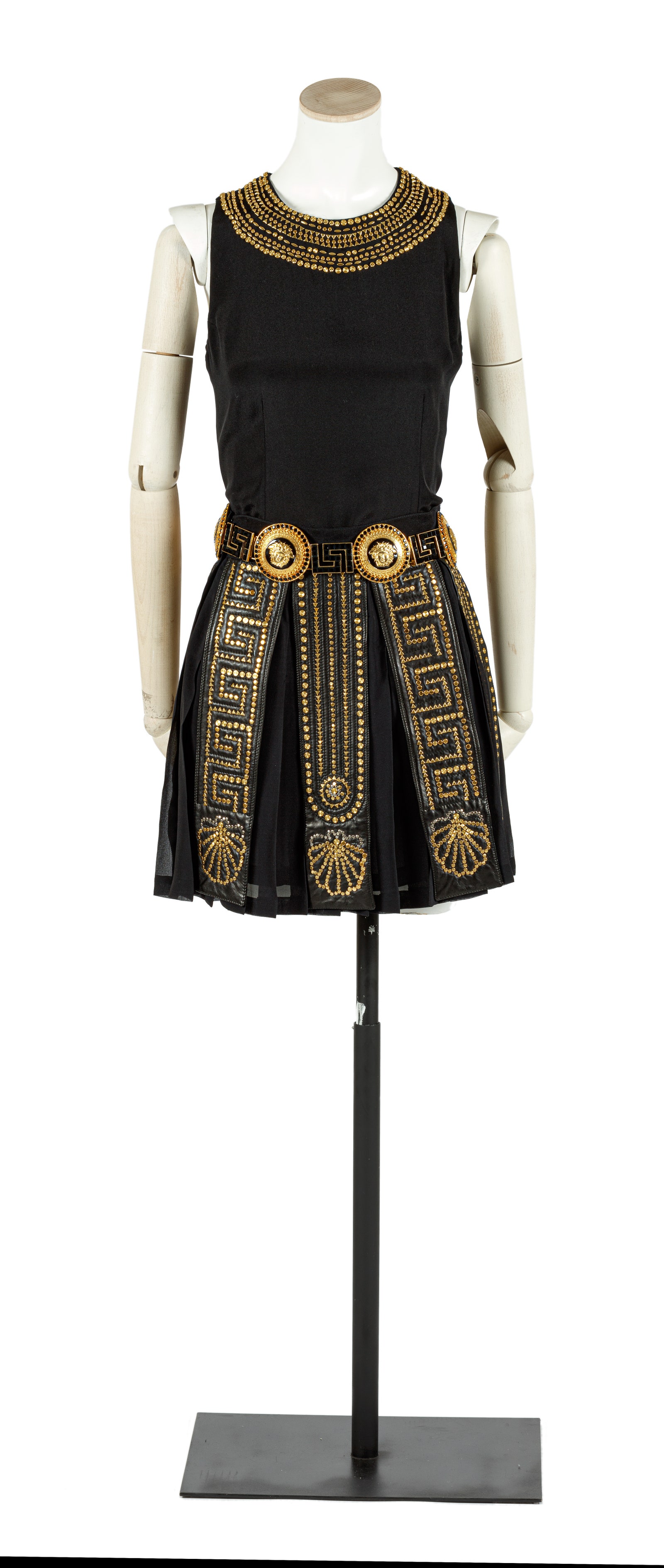 Traje negro compuesto por camisa sin mangas y adornos de pedrería dorada en cuello falda con tiras de cuero y adornos...