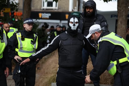 Un agente de policía registra a una persona enmascarada en Walthamstow, al noreste de Londres, el 7 de agosto. 