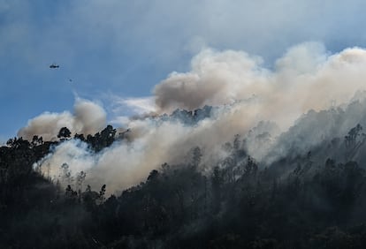 Un helicóptero lanza agua sobre la zona del incendio en el municipio de Baiao, este lunes. 