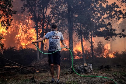 Un hombre usa una manguera para extinguir el incendio en Oliveira De Azemeis, este lunes.
