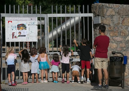 Varios niños observan el parque infantil cerrado de La Boni, en Manzanares el Real, este martes.