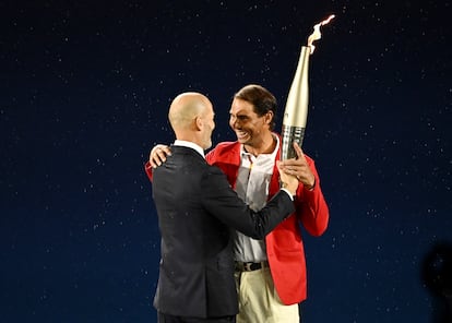 El exfutbolista y entrenador francés Zinedine Zidane pasa la antorcha olímpica al tenista español Rafael Nadal, durante la ceremonia de inauguración de los Juegos Olímpicos de París, el 26 de julio. 