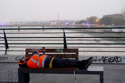Un hombre descansa en uno de los puentes de acceso a Valencia, con el Turia de fondo.