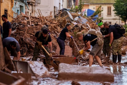Residentes y voluntarios limpian una calle afectada tras el paso de la dana en Valencia, este sábado.