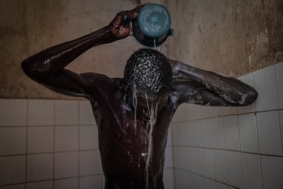 Mamadou se ducha en los aseos de un mercado cercano al lugar donde duerme, en el barrio de Patte d'Oie de Dakar el 6 de julio.