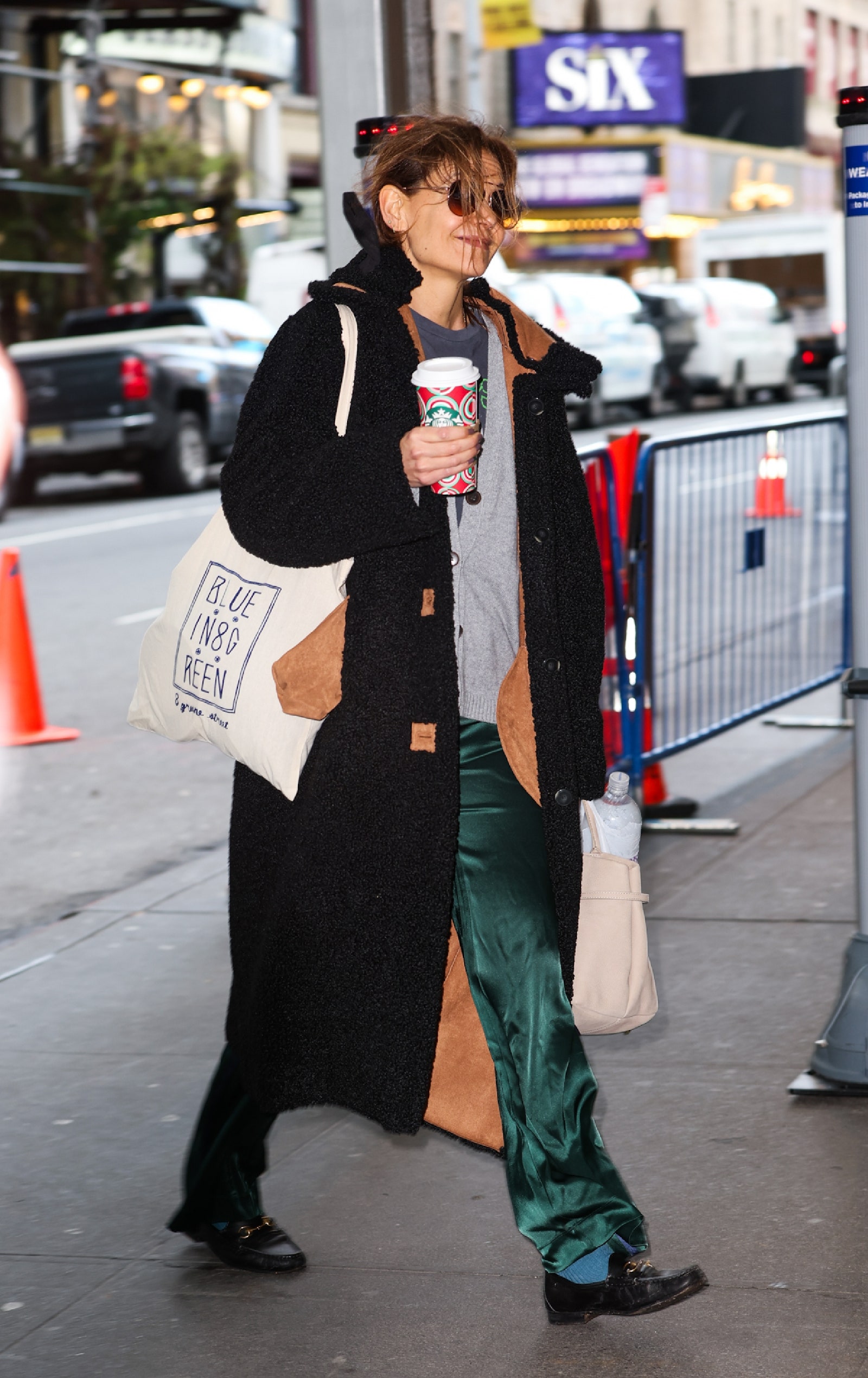Katie Holmes con un estilismo compuesto por un cardigan gris unos pantalones satinados en color verde botella y unos...