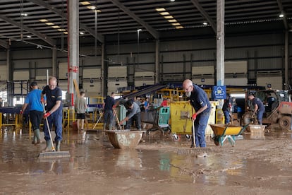 Trabajadores de una empresa de logística limpian el interior de una nave, en el polígono industrial de Riba-roja, en Turia.