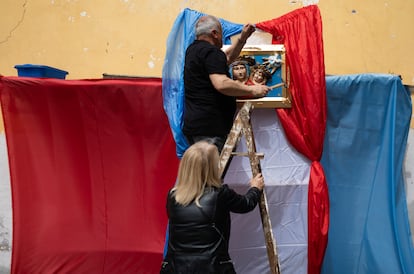 En el centro histórico de Nápoles, dos vecinos arreglan un altar en la fachada de su casa, durante la Semana Santa de 2023.