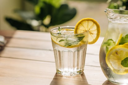 Cool freshly made lemonade and fruits on grey wooden table.