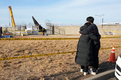 Familiares de una de las víctimas del avión siniestrado contemplan los restos del fuselaje en el aeropuerto de Muan, este lunes.