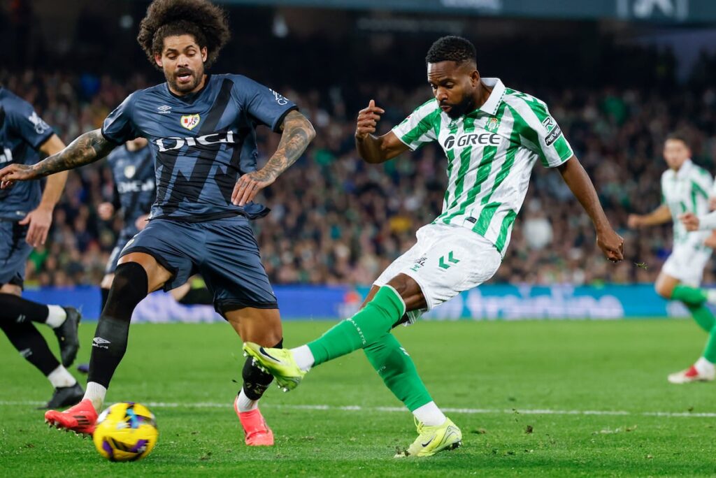 El delantero del Betis Bakambu dispara a la puerta del Rayo ante la oposición de Aridane.