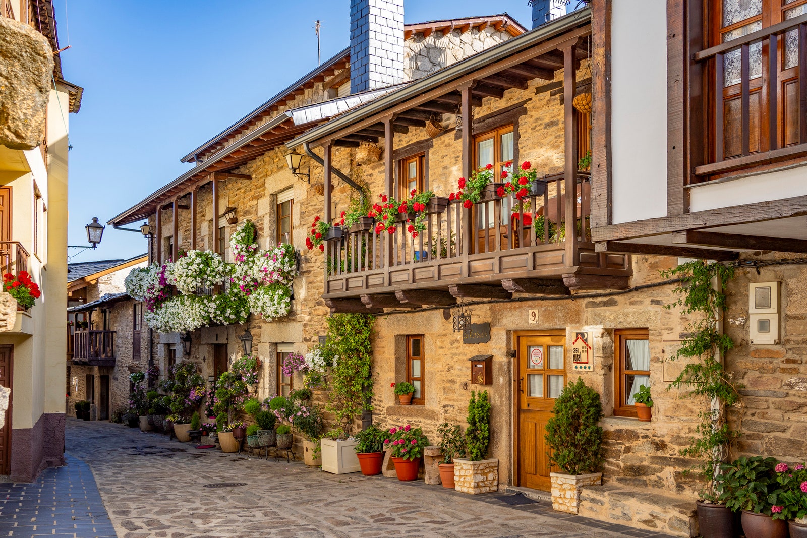 Cobblestone street with picturesque stone residential buildings and flowered balconies in Puebla de SanabrÃ­a Zamora...