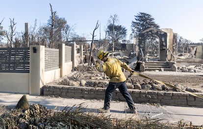 Bomberos trabajan en la zona devastada por el  incendio refrescando zonas quemadas para evitar la aparición de nuevos fotos en Sunset Boulevard, en Los Ángeles. 