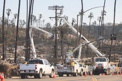 Trabajadores de la compañía eléctrica trabajan en la zona quemada en el incendio en la carretera que recorre la playa en Pacific Palisades.