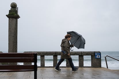 Dos personas se refugian de la lluvia con paraguas en la comarca de Salnés (Pontevedra).