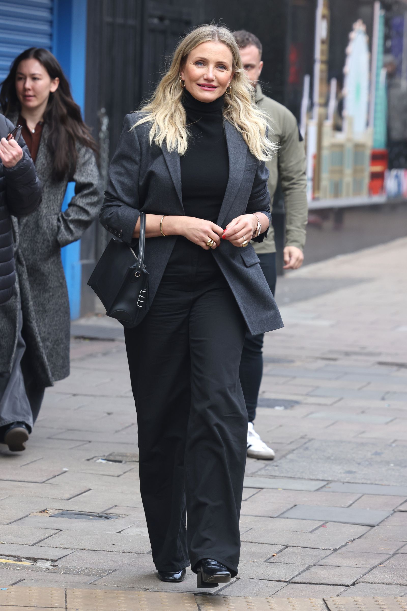 Cameron Diaz con una americana gris y unos pantalones de pinzas negros