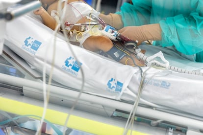 Un sanitario atiende a uno de los pacientes de la UCI pediátrica del hospital de La Paz. 