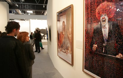 Unos visitantes pasan ante dos fotografías obra de Joan Fontcuberta, en el 'stand' de EL PAÍS, en la feria de arte ARCO 2007.