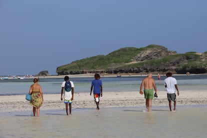 Tres 'beach boys' acompañan a una pareja de turistas europeos en la playa de Watamu, el 25 de diciembre de 2024.