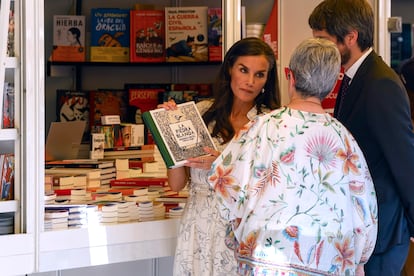 La reina Letizia recomendando el libro 'La piedra blanca', de Rodrigo Cortés y Tomás Hijo, al ministro de Cultura Ernest Urtasun y la directora de la Feria Eva Orúe. 