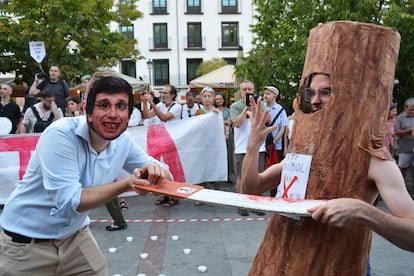 Un hombre que imita a Almeida simula talar a otro disfrazado de árbol durante la protesta en la plaza de Santa Ana, el 23 de julio de 2024. En la imagen aún se ven árboles que ya no están.