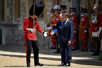El rey Carlos III del Reino Unido y un guardia real hacen un gesto junto al presidente de Francia, Emmanuel Macron. 