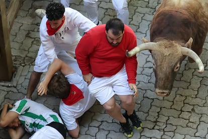 Varios corredores caen al suelo al paso de uno de los toros de la ganadería Victoriano del Río Cortés durante el cuarto encierro.
