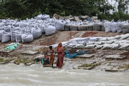 Una mujer y dos niños de pie sobre bloques de cemento que evitan las inundaciones y la erosión en la orilla del río Yamuna en Sirajganj, el pasado mayo.