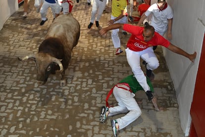 Varios mozos junto a uno de los toros de la ganadería Victoriano del Río Cortés en el callejón de entrada a la plaza de toros de Pamplona. 
