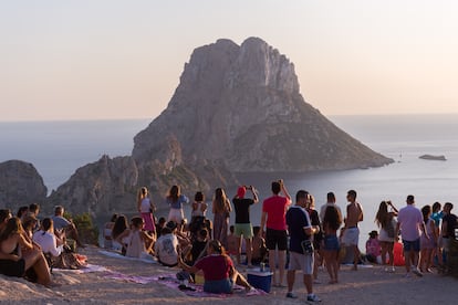 Grupos de personas disfrutan del atardecer en Ibiza frente al misterioso islote de Es Vedrà.