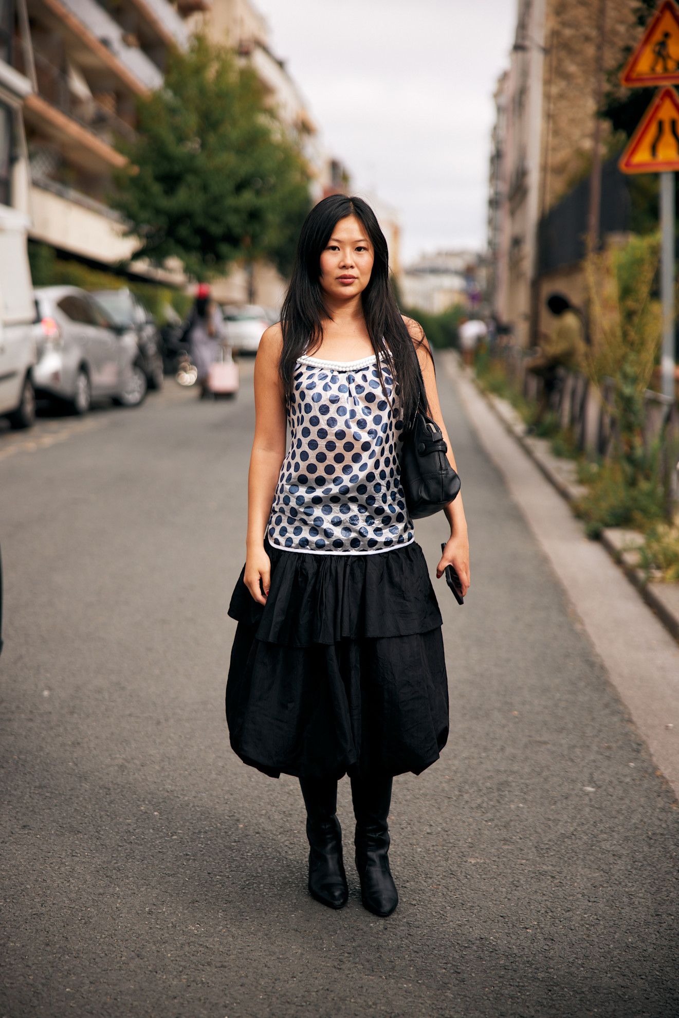 Image may contain Clothing Pants Person Teen Accessories Bag Handbag Skirt Electronics Mobile Phone Phone and Car
