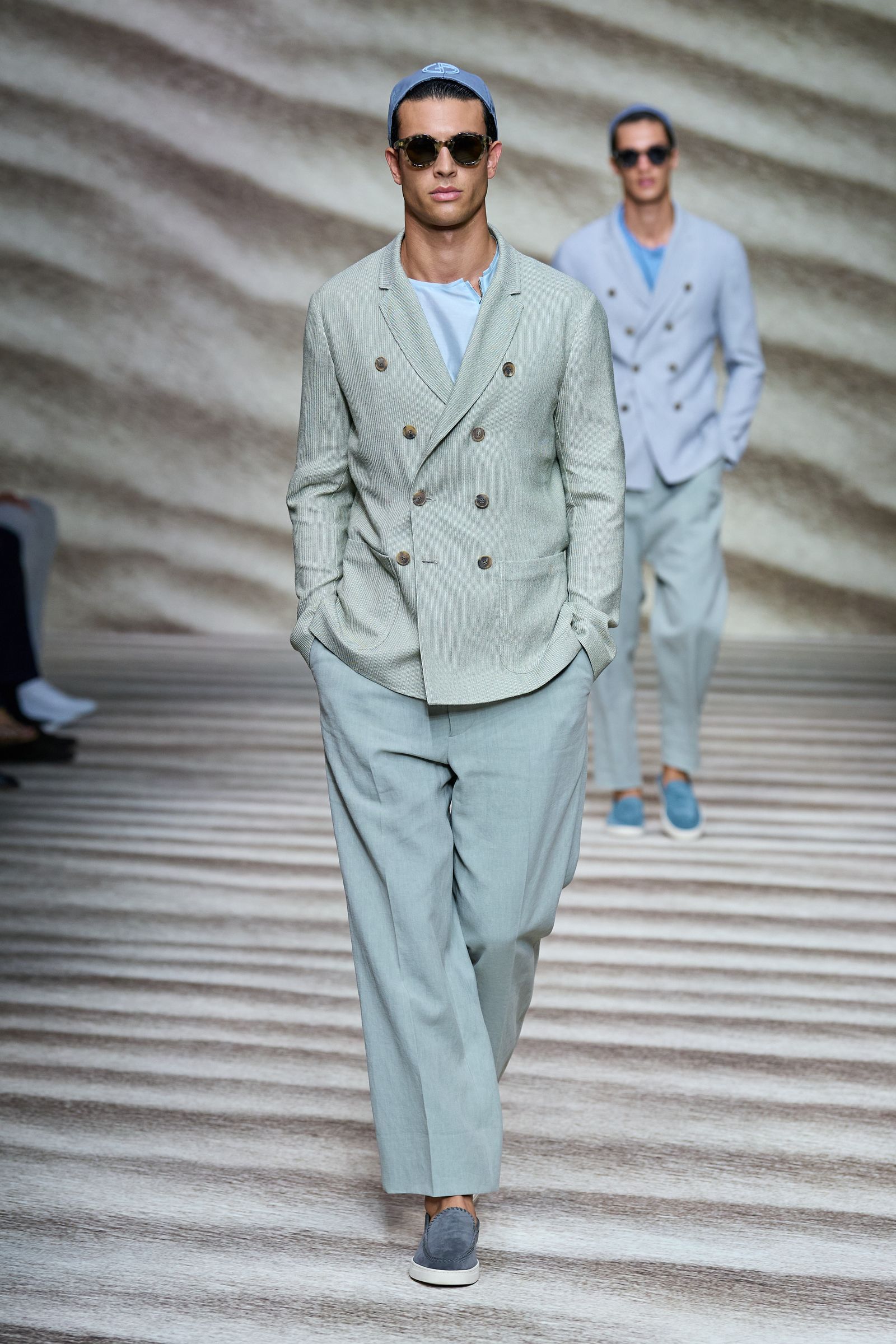 Image may contain Suit Coat Clothing Overcoat Apparel Human Person Sunglasses Accessories Accessory and Footwear