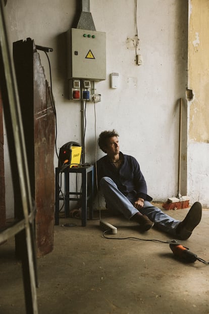En el silo donde se ubica su nuevo taller, la radial en el suelo y una pieza de madera y acero destinada a la obra en la que trabaja por encargo de una bodega de Oporto, el escultor se toma un respiro.