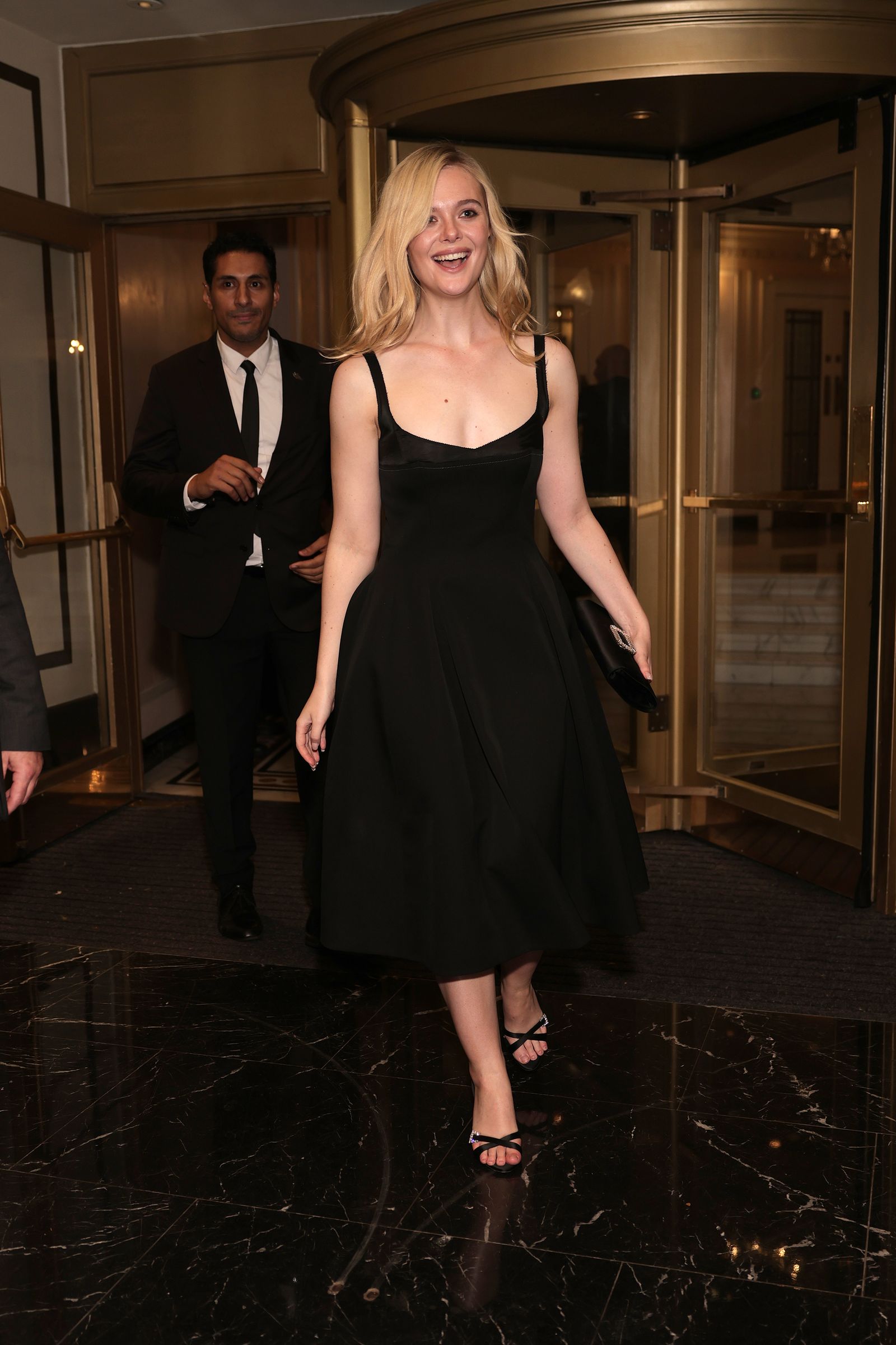 Elle Fanning con un vestido midi negro y unas sandalias dosmileras