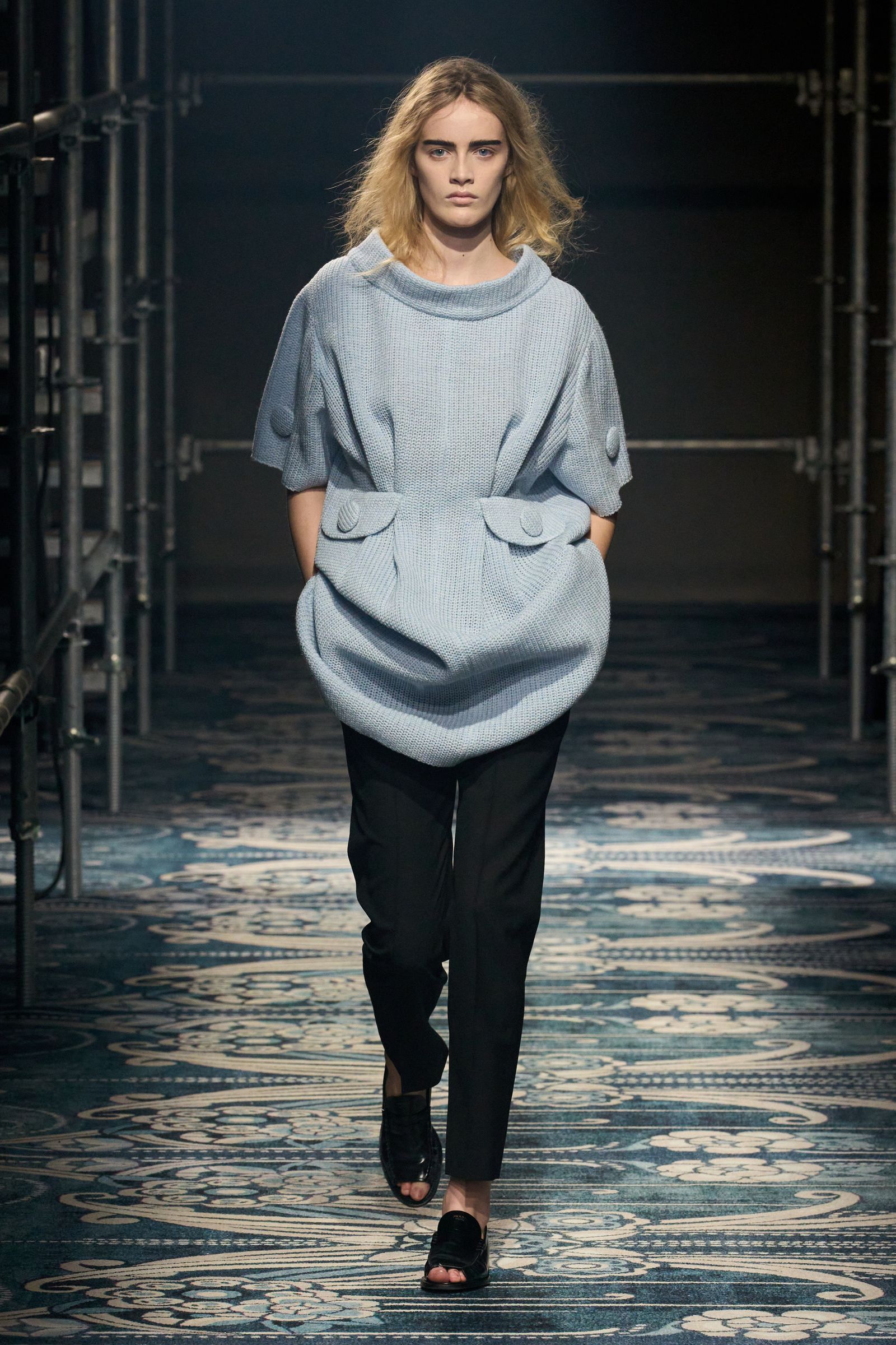 Image may contain Clothing Pants Adult Person Sleeve Blouse Standing Knitwear Sweater Footwear and Sandal