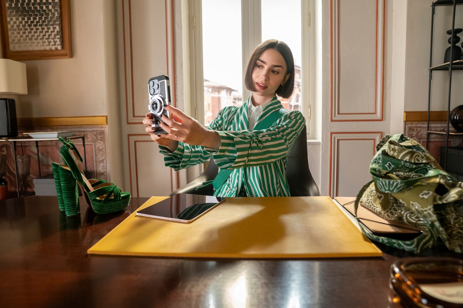 Image may contain Lily Collins Camera Electronics Furniture Table Adult Person Desk Face Head Accessories and Bag