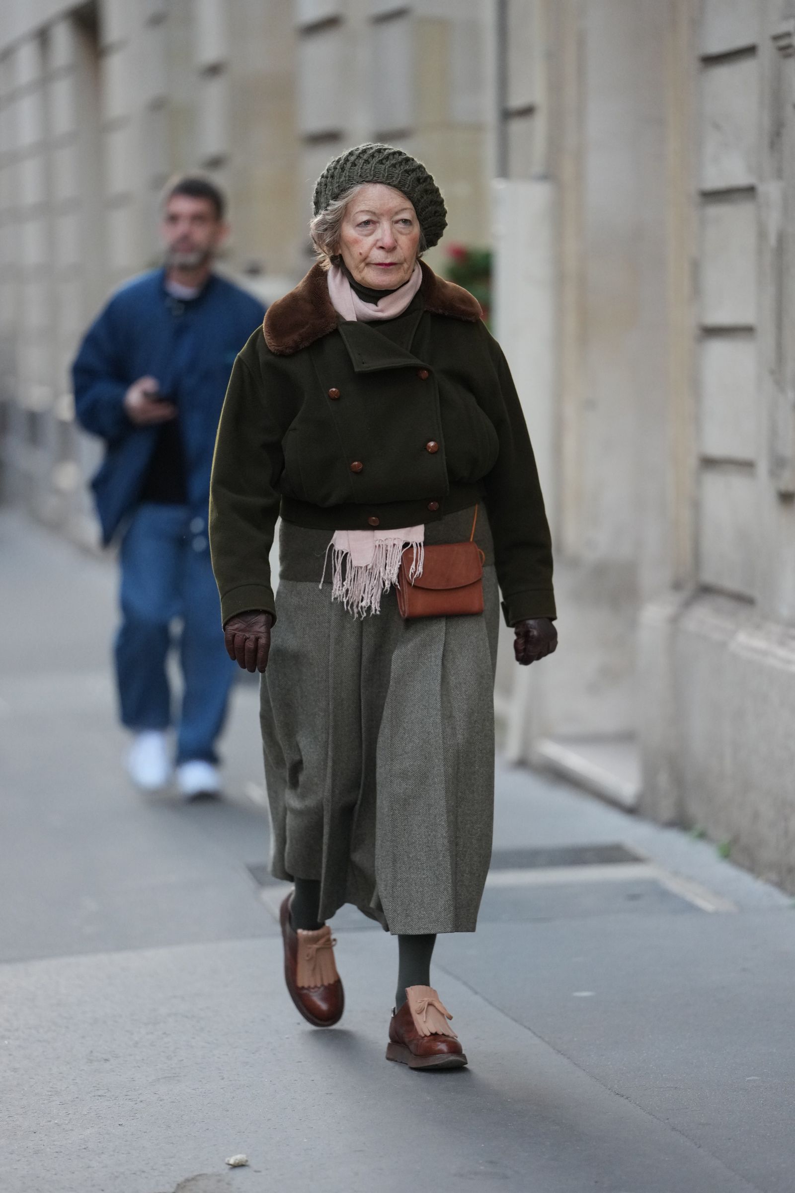 PARIS FRANCE  JANUARY 2026 A guest wears short gray hair styled in soft waves under a green olive knit beret hat a brown...