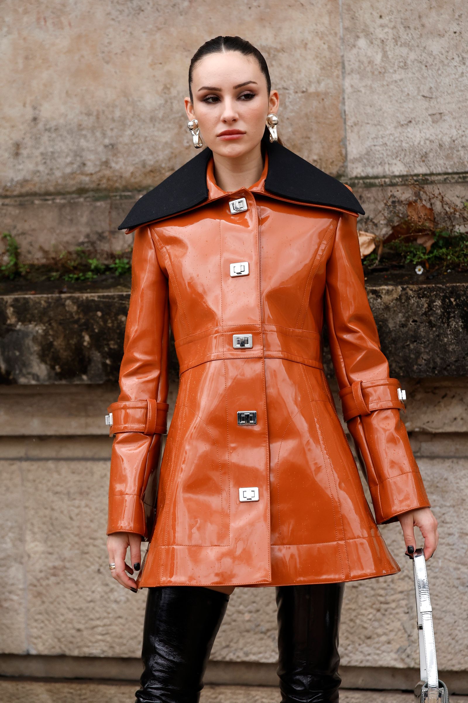 PARIS FRANCE  JANUARY 25 Ashtin Earle wears orange patent leather coat with black collar silver bag black over the knees...