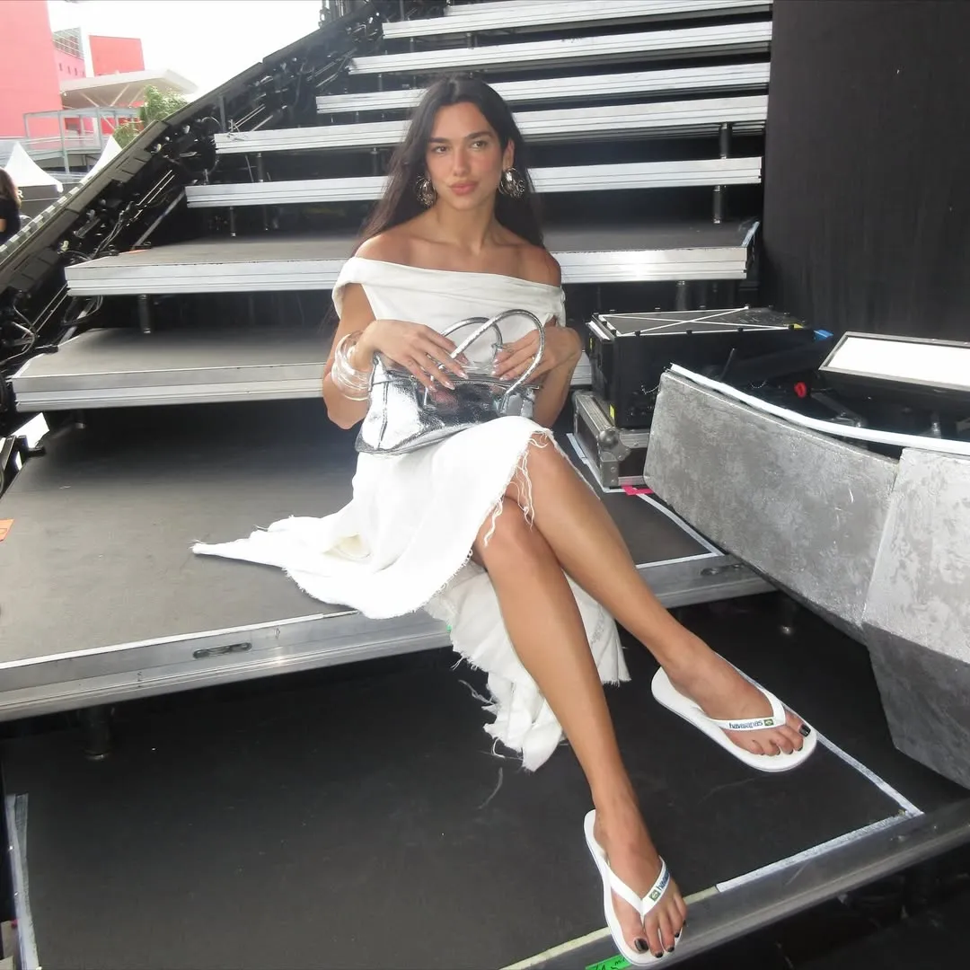 Image may contain Dua Lipa Person Sitting Racket Sport Tennis Tennis Racket Clothing Footwear Sandal and Adult