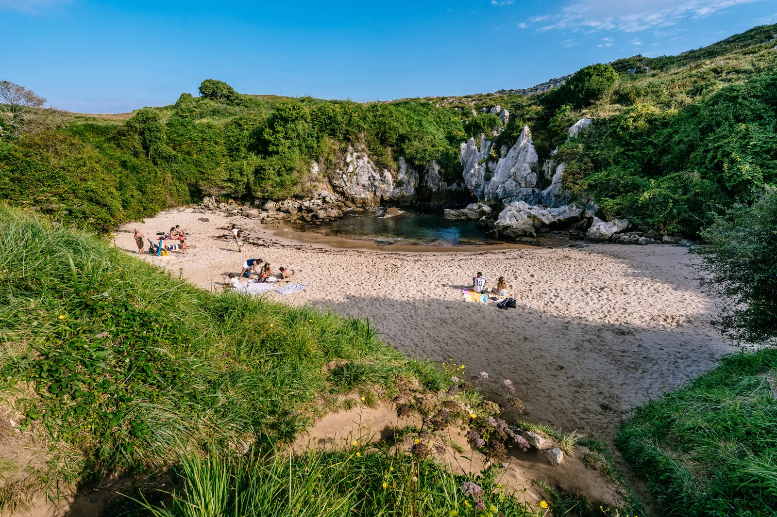 LLANES ASTURIAS SPAIN  20190824 People having sun in Gulpiyuri beach  a flooded sinkhole with an inland beach.